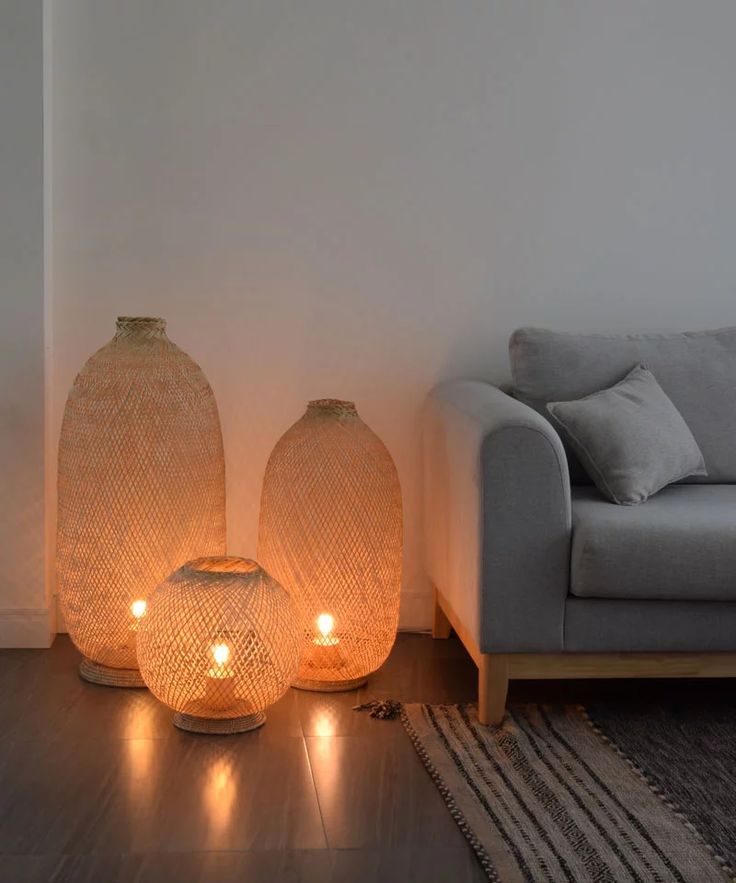 two vases sitting next to each other on a wooden floor in front of a couch