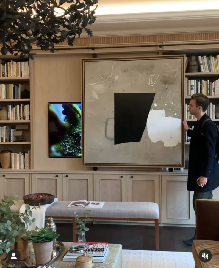 a man standing in front of a large painting on the wall next to a couch