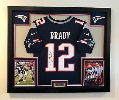 a football jersey is in a shadow box with two photos and an autographed card