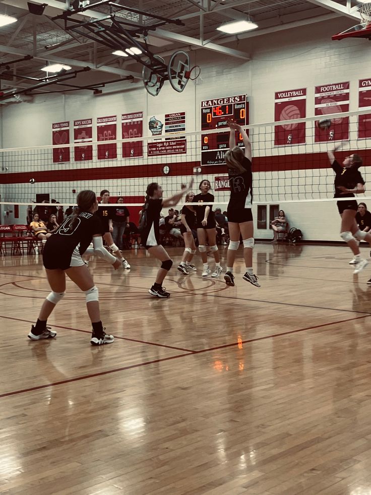 girls playing volleyball in a gym during the day