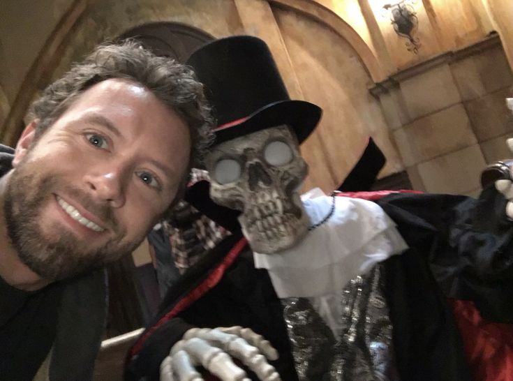 a man in a top hat and costume poses with a skeleton