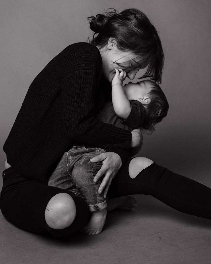 a woman sitting on the ground holding a baby