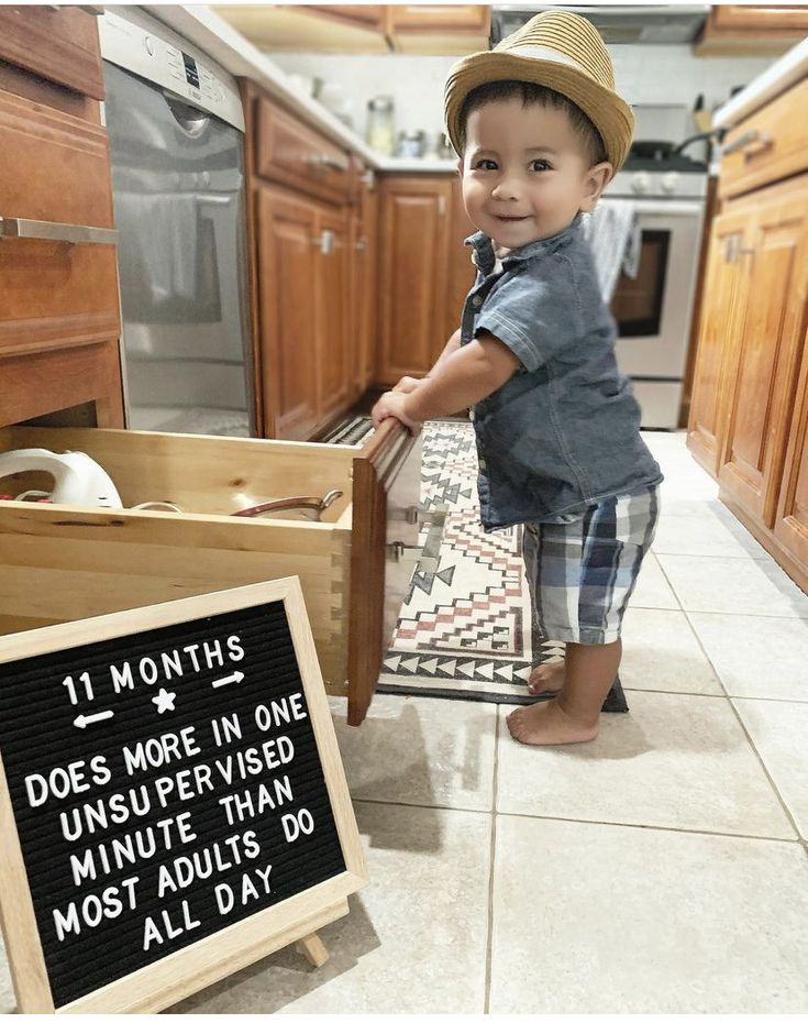 a little boy that is standing in front of a dishwasher with a sign