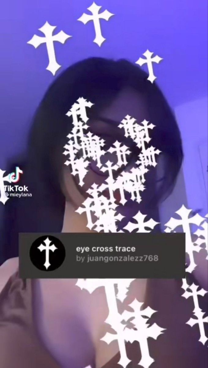 a woman with dark hair and glasses is looking at the camera while she has white crosses on her face