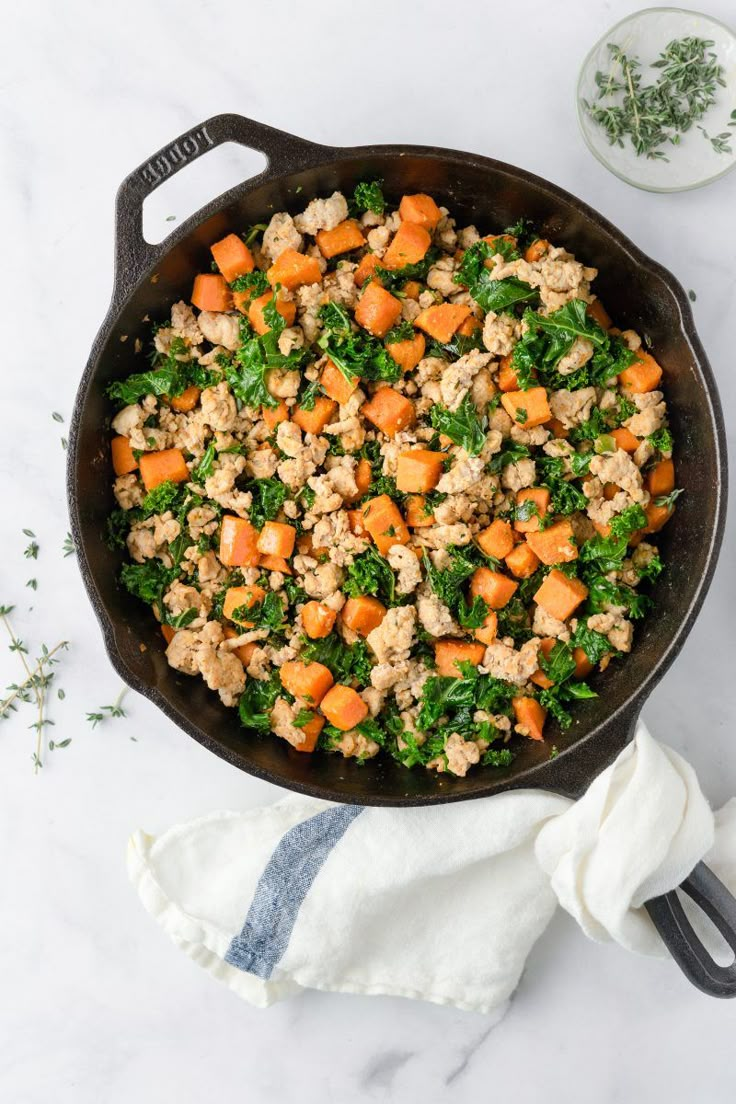 a skillet filled with meat and vegetables on top of a white counter next to a napkin