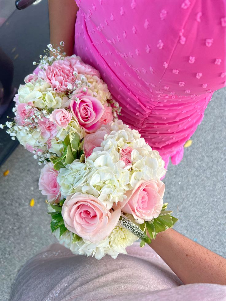 a woman in a pink dress holding a bouquet of white and pink flowers on her arm