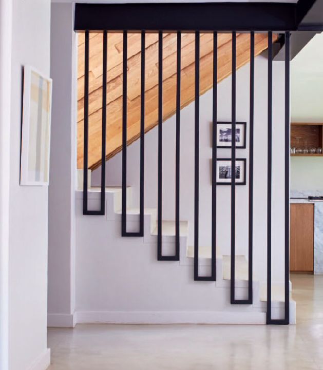 an open stair case with pictures on the wall next to it and a kitchen in the background