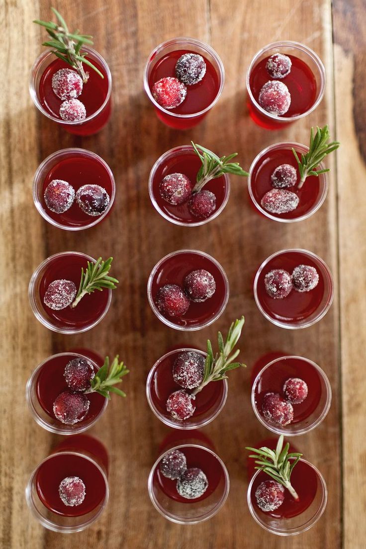 several glasses filled with different types of drinks on top of a wooden table and garnished with sprigs