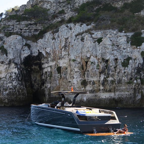 a small boat in the water near a rocky cliff face with a table on it