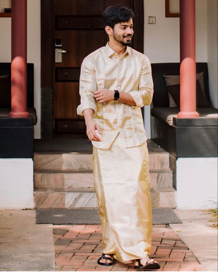 a man standing in front of a door wearing a white and gold outfit with black shoes