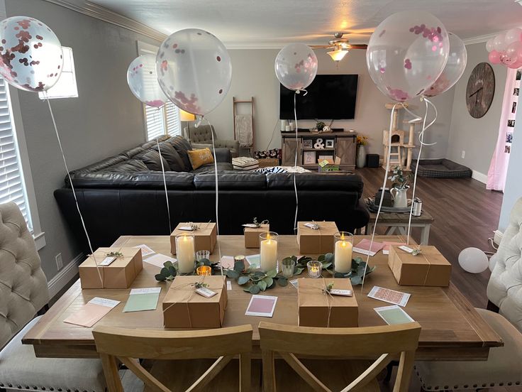 a living room filled with lots of balloons and boxes on top of a wooden table