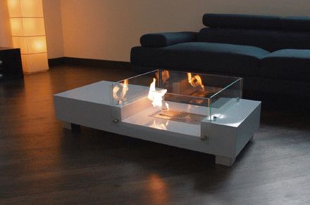 a glass fire pit sitting on top of a hard wood floor next to a couch