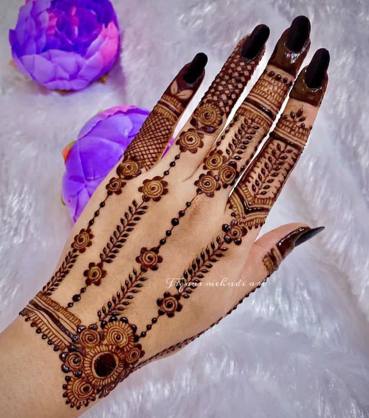 henna tattoo on the hand of a woman with purple flowers in the foreground