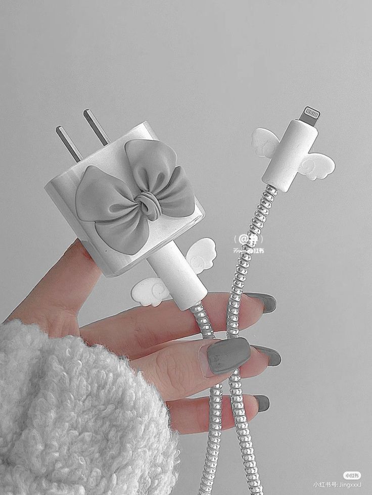 a person holding two electrical plugs in their hands, one with a bow on it