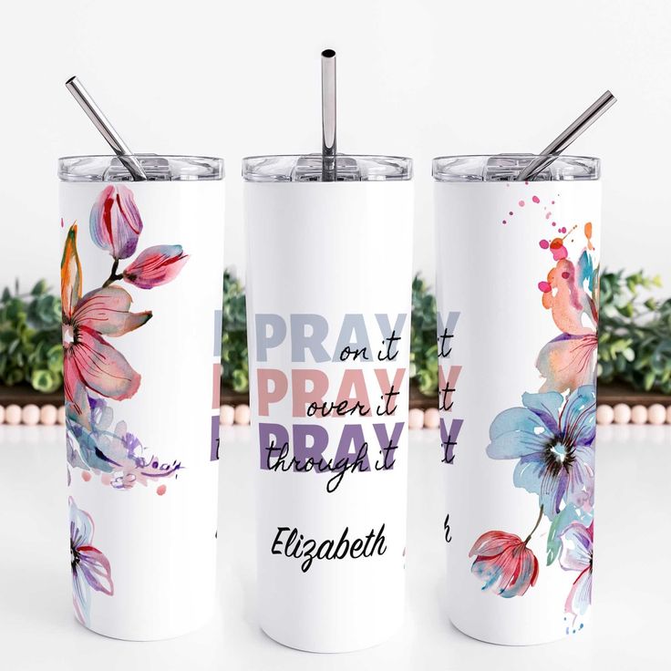 two white tumblers with colorful flowers and words on them, one has a straw in it