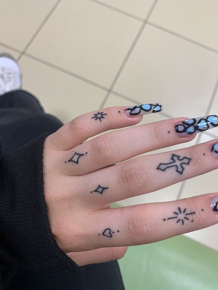 a woman's hand with tattoos on it and two fingers that have small stars