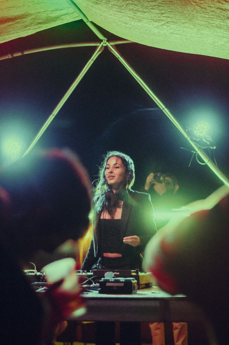 a woman standing in front of a table with lights on it and people around her