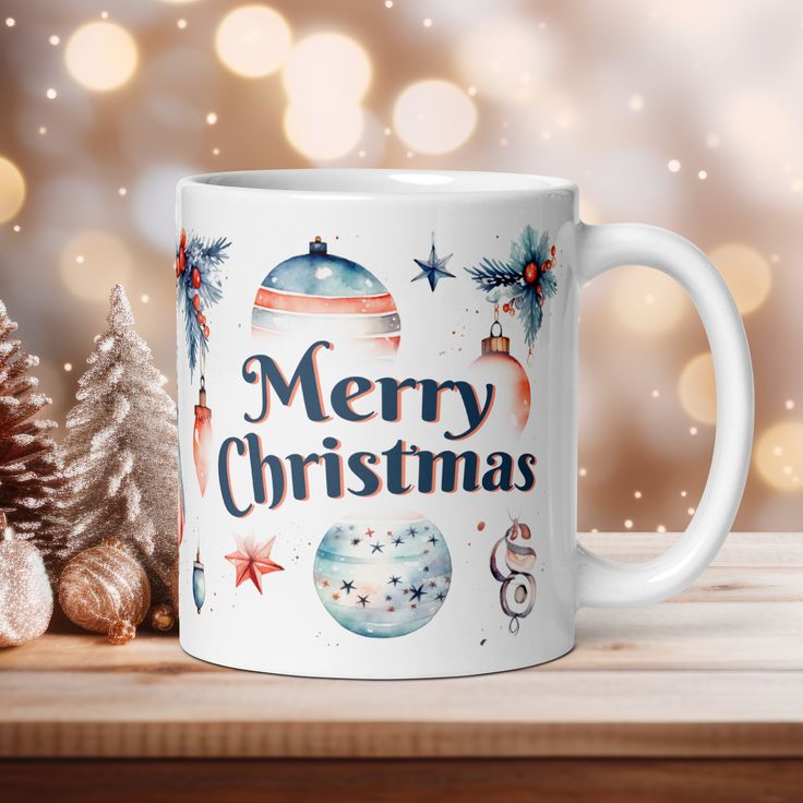 a white coffee mug sitting on top of a table next to a christmas tree and ornaments