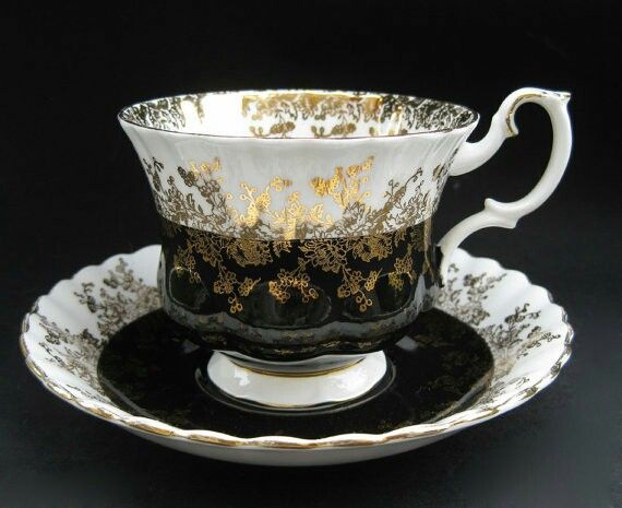 an ornate black and gold tea cup with saucer