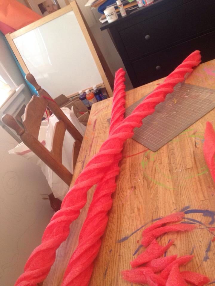 a wooden table topped with red yarn and a pair of scissors on top of it