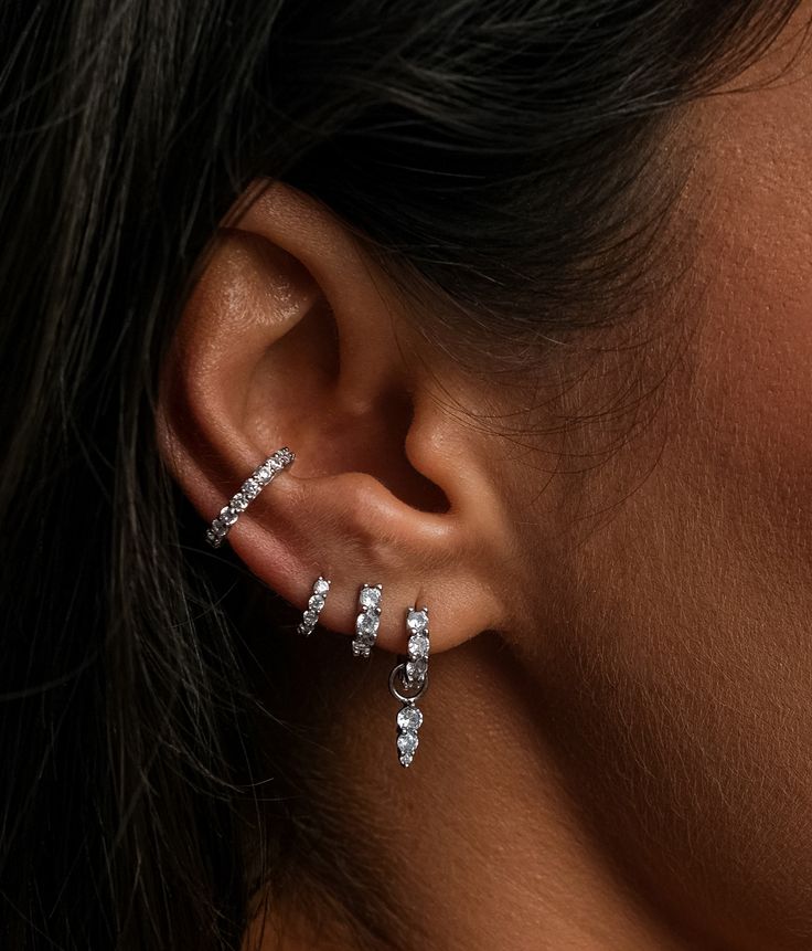 Meet the Skye Hoop, our most sparkling earring yet. Crafted from sterling silver and adorned with cubic zirconia, these hoops are designed to let as much light in as possible, making them truly sparkle from every angle. Available in three versatile sizes—8mm, 6.5mm, and 5.5mm—these hoops are perfect for stacking or wearing in cartilage piercings, allowing you to create a personalised ear stack that shines. Whether worn solo or layered with other pieces, the Skye Hoop is destined to become your go-to earring for adding a touch of brilliance to any look.Sold As A Single Hoop Earring.Maya Spike Charms Fits All Hoop Sizes.Materials: 925 Sterling Silver With a Rhodium Plating FinishGems: 2.5mm White Cubic Zirconia Stones Lower Ear Piercing, Stacked Earrings Silver, Sterling Silver Ear Stack, Ear Lobe Piercings Triple, Silver Jewelry Earring Stack, Elegant Piercings Ears, Wedding Earring Stack, Bridal Earring Stack, Silver Earring Stack Prom