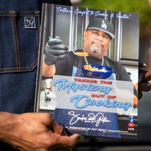 a man holding up a book about cooking