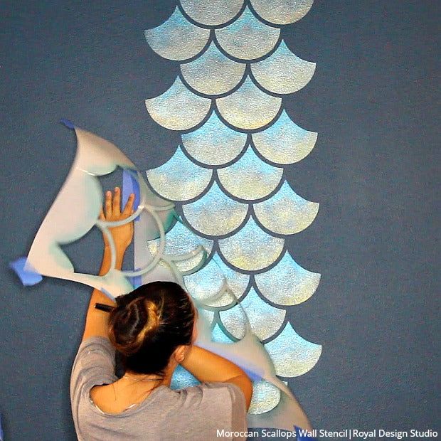 a woman is painting a fish on the wall with acrylic paint and stencils