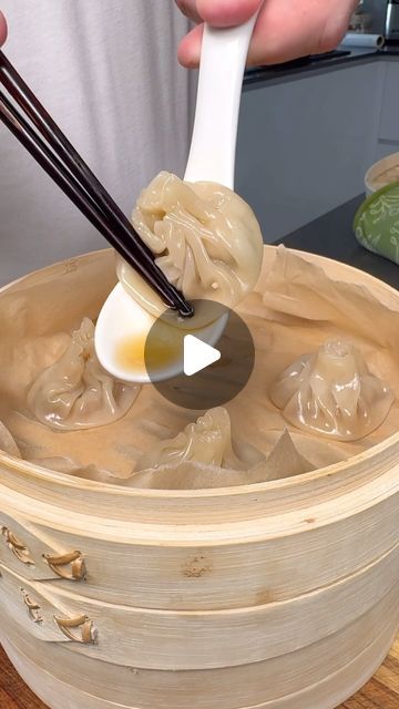 a person holding chopsticks over a bowl filled with dumplings