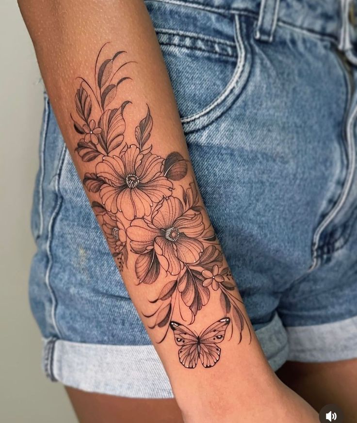 a woman's arm with flowers and butterflies tattooed on the left side of her arm