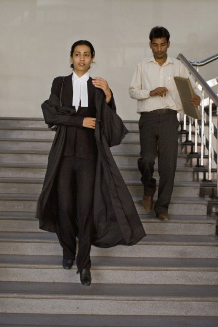 a woman walking down some stairs with another man in the background