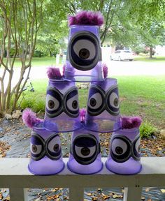 there is a tower made out of purple and black cups with eyes on the top