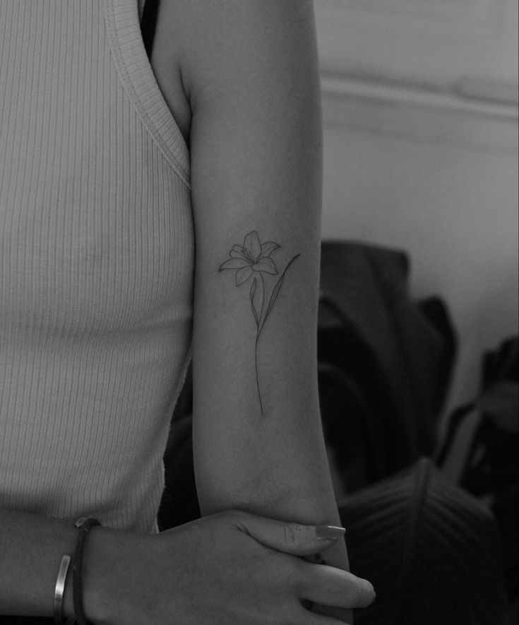 a woman's arm with a small flower tattoo on the left side of her arm