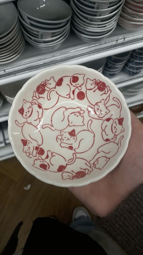 a hand holding a red and white plate with bears on it in front of plates