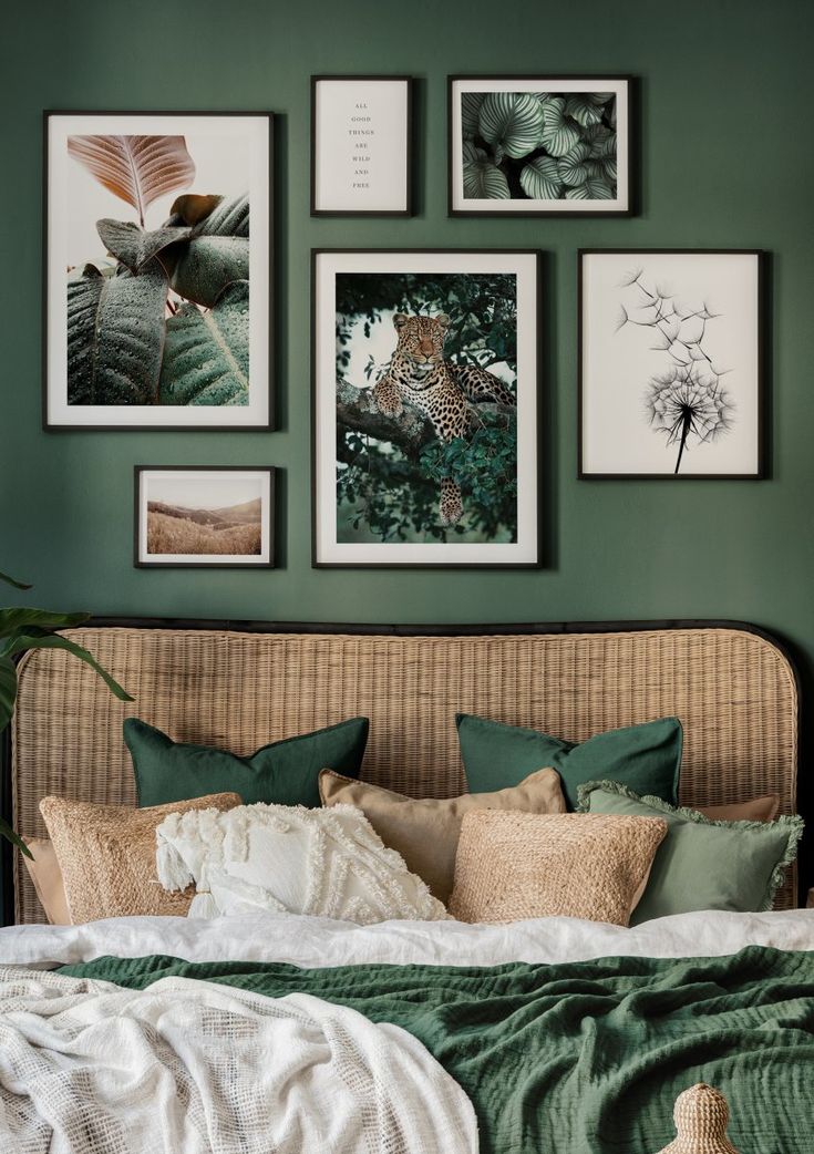 a bedroom with green walls and pictures on the wall above the bed, along with wicker furniture