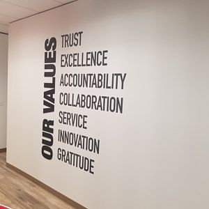 an office with white walls and wood flooring is decorated with black words that spell out our value