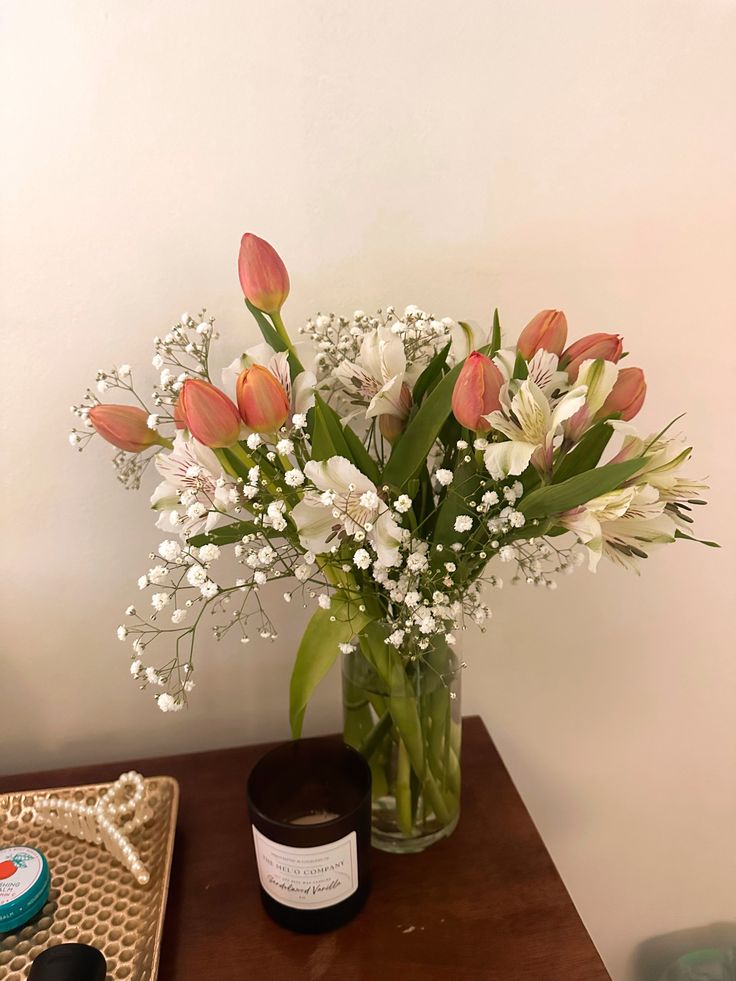 a vase filled with flowers sitting on top of a table next to a jar of cream