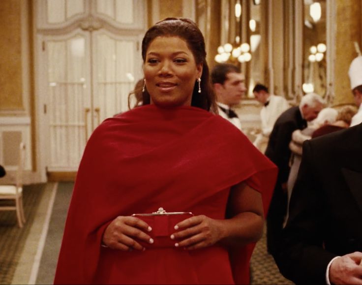 a woman in a red dress standing next to a man in a tuxedo