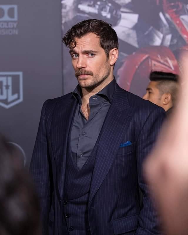 a man in a suit and tie standing next to other people at a red carpet event