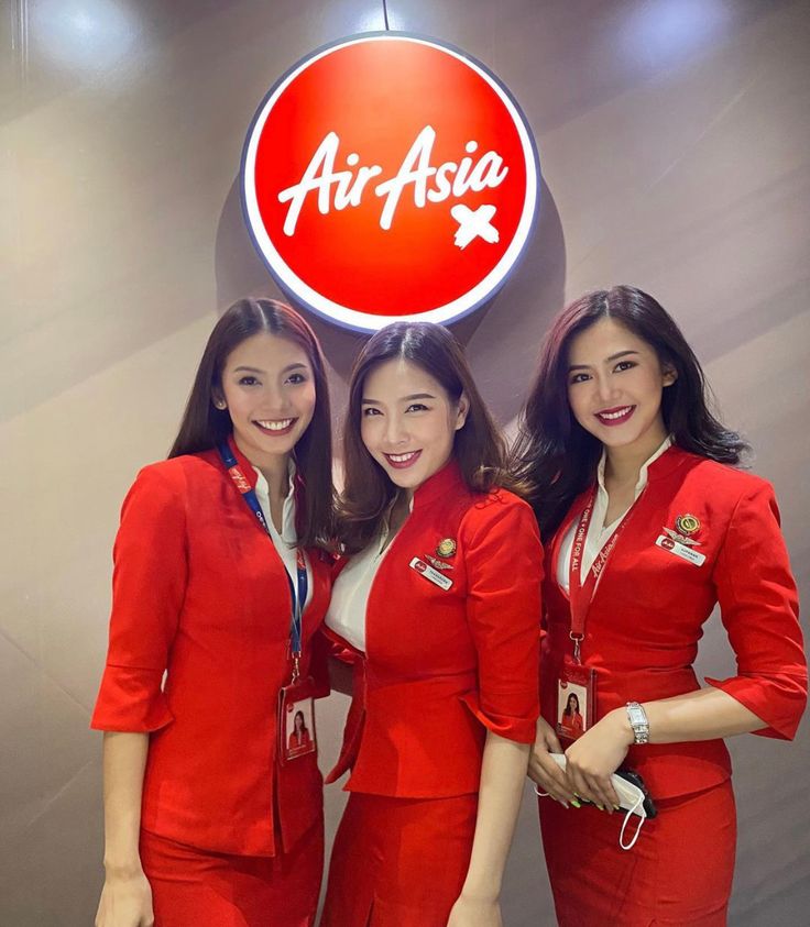 three air asia flight attendants standing in front of an airplane sign with the word air asia on it