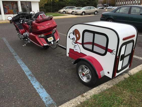 a red motorcycle pulling a trailer with a dog on the side and a scooter behind it