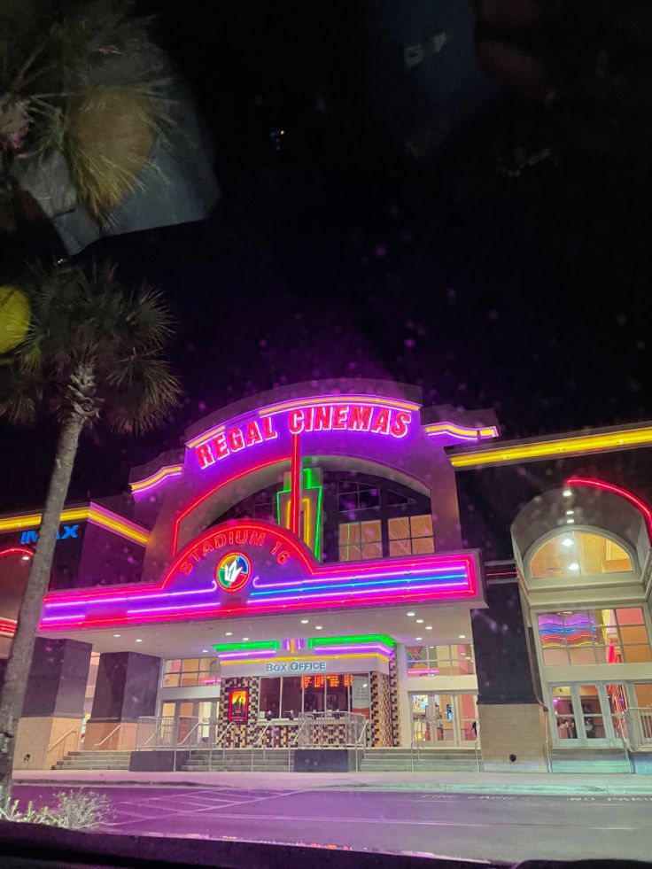 a building with neon lights and palm trees