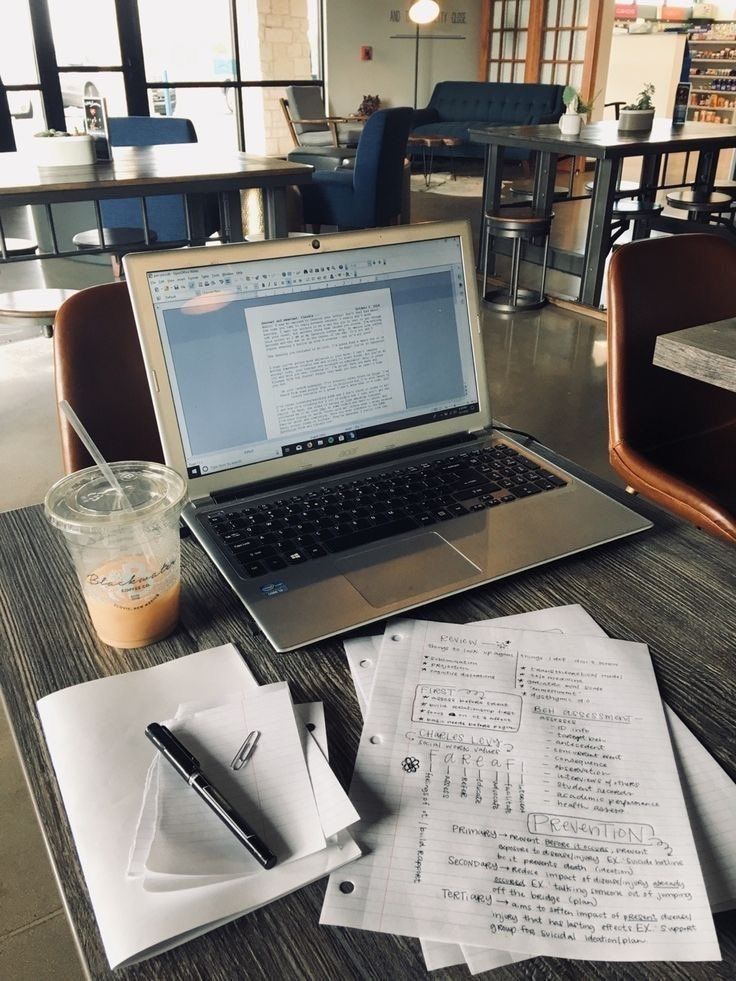 an open laptop computer sitting on top of a table next to papers and a pen