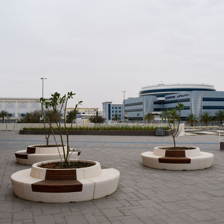 three planters with small trees in them sitting on the ground next to a building