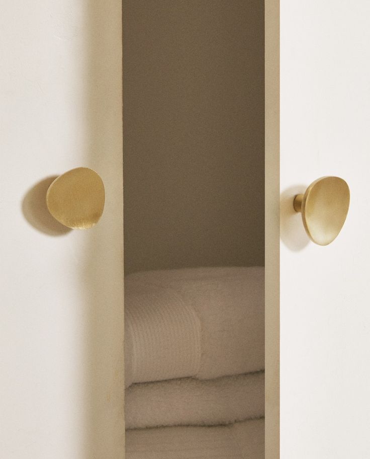 the door is open to reveal towels and folded linens in a white closet with gold knobs