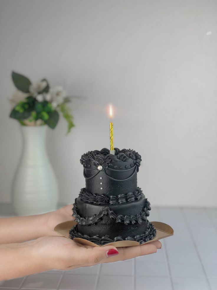 a person holding a cake with a candle in it