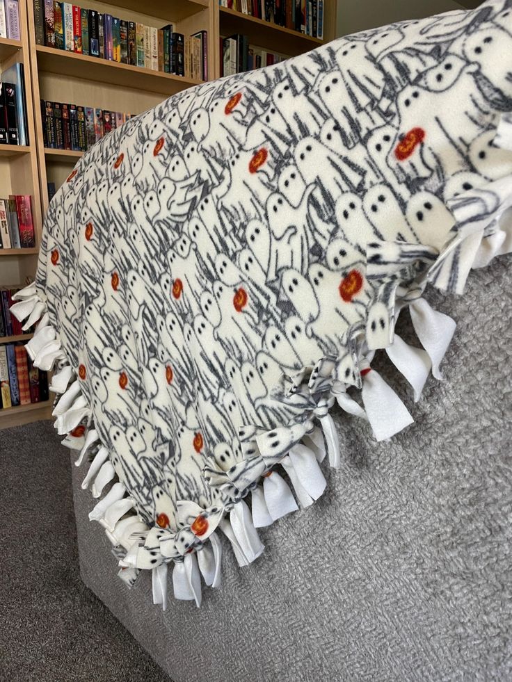 there is a pillow with cats on it in front of bookshelves and shelves