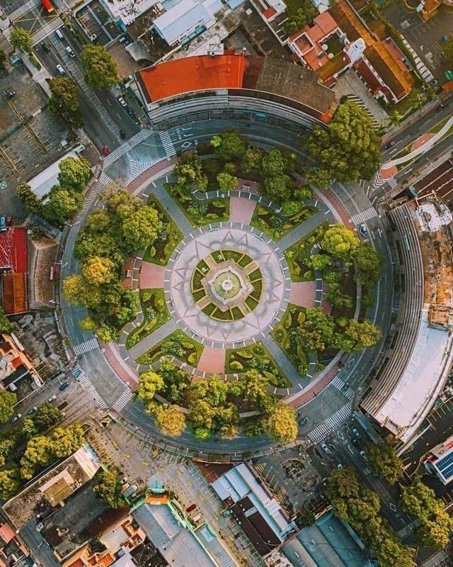 an aerial view of a circular building with trees in the center and other buildings around it