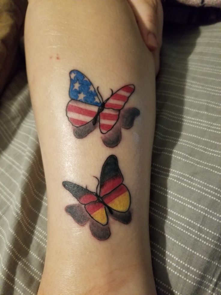 two butterflies with american flags on their wings are sitting next to each other in front of a woman's leg