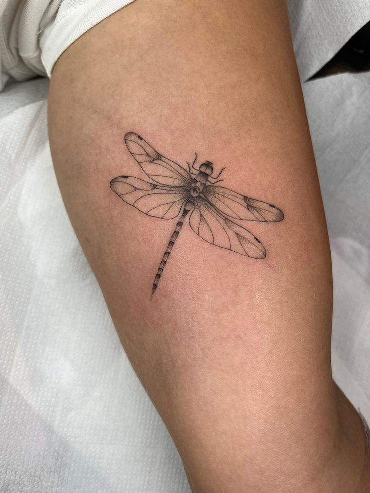 a small dragonfly tattoo on the leg