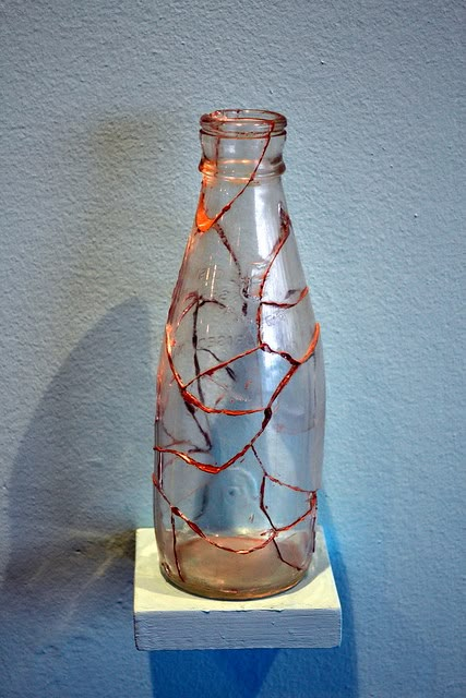 a glass bottle sitting on top of a white shelf next to a blue painted wall